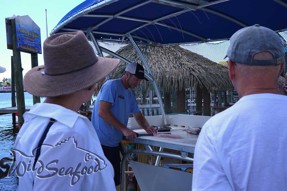 Wild Seafood Market crew member Chris filleting fish for customers at our market's dock