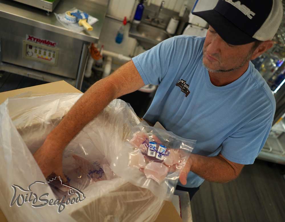 Crew member packing shipping cooler box with fish at the Wild Seafood Market